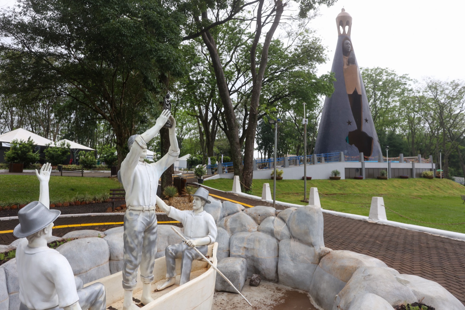 Esculturas dos pescadores que encontraram a imagem original de Nossa Senhora Aparecida, com o monumento ao fundo